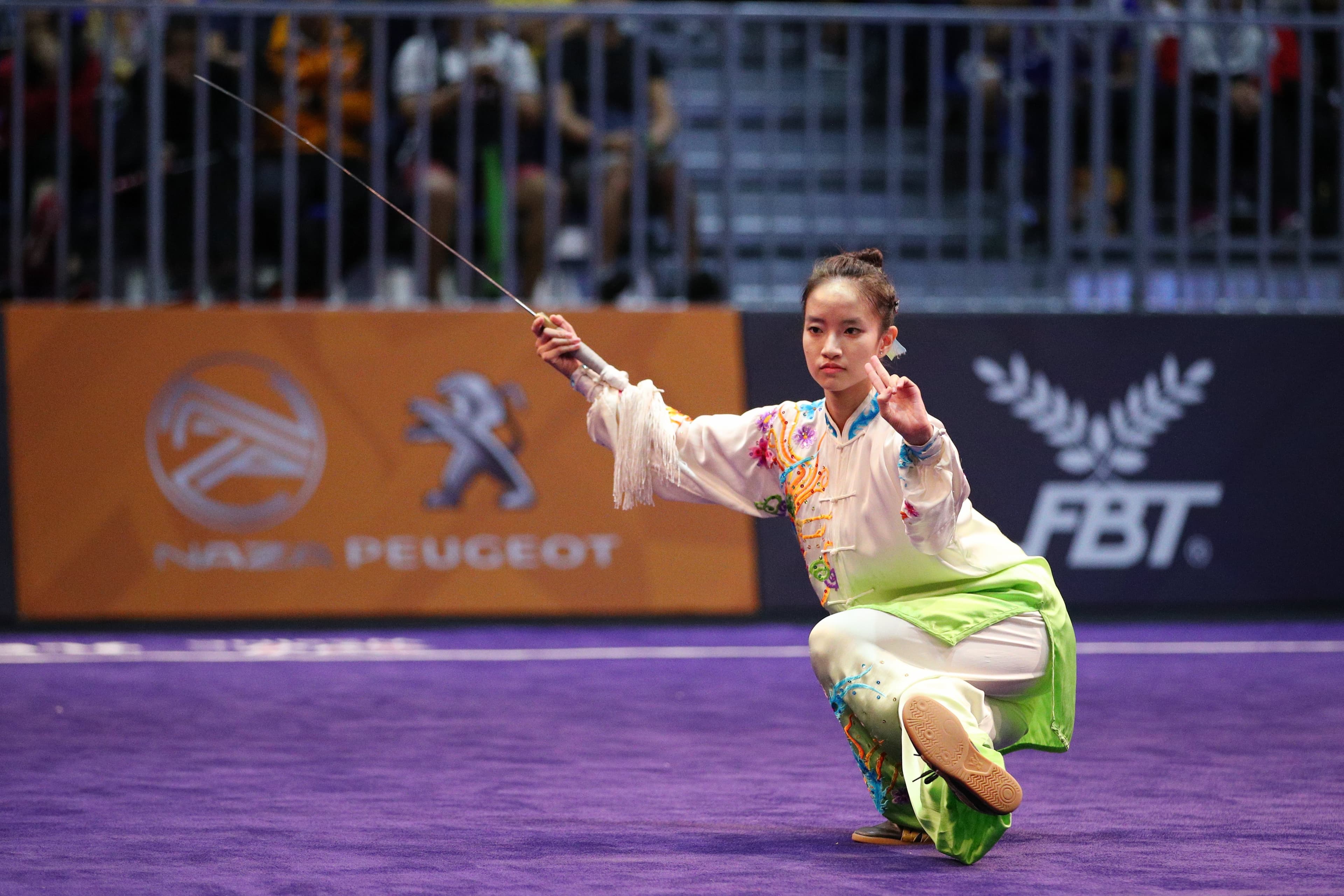Sino Wushu athlete performing a sword form at an international wushu competition